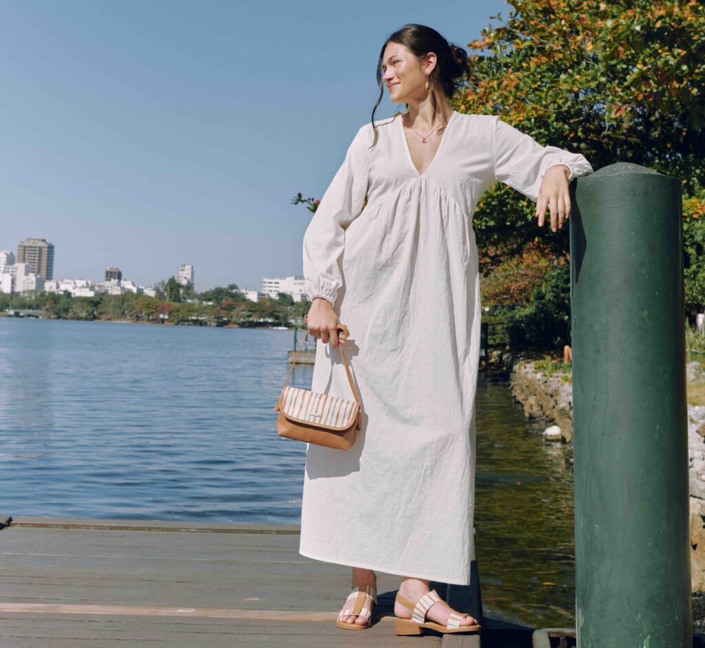 Mulher com vestido branco, com sandalia e bolsa 